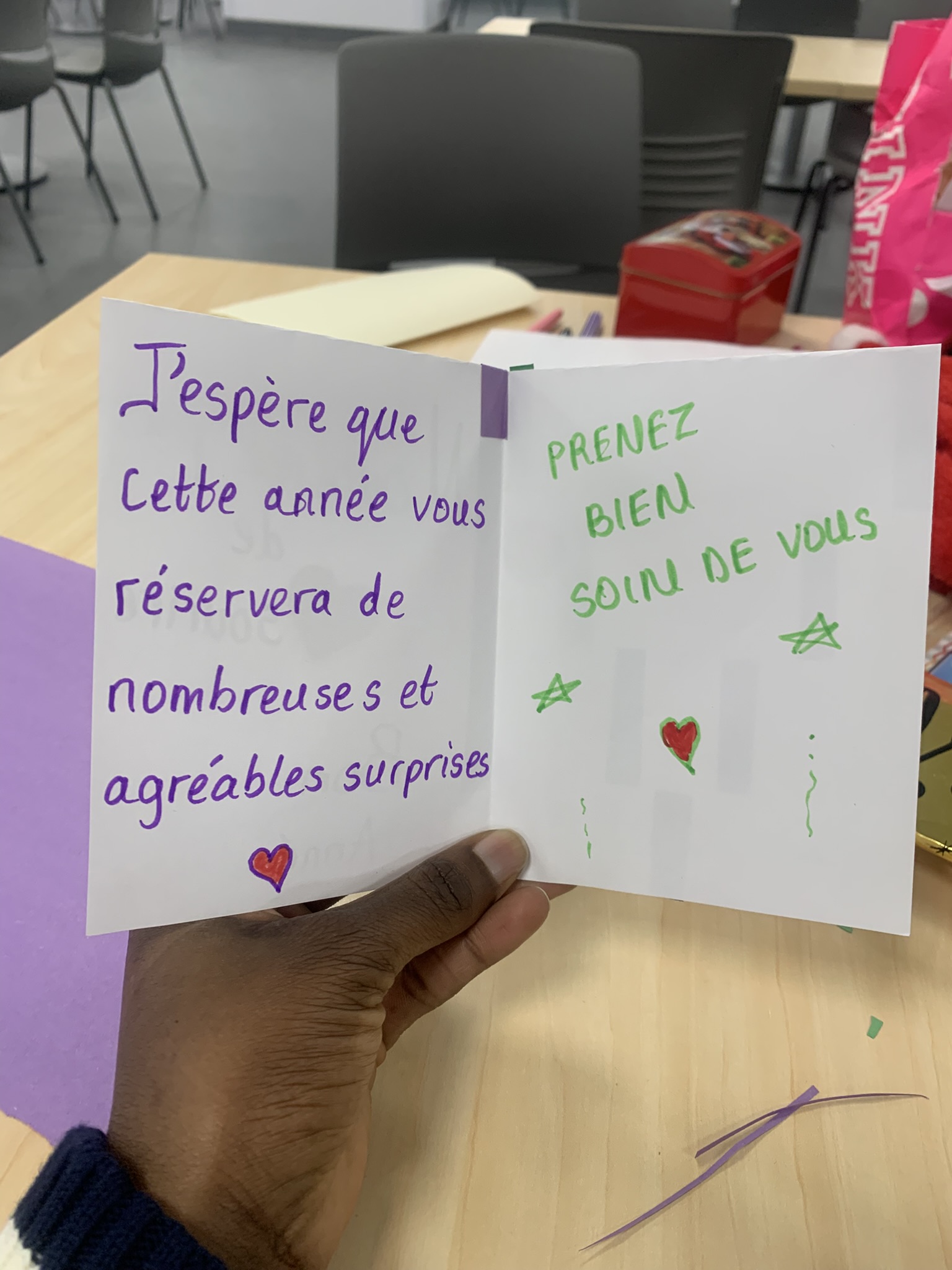Bilingual New Year's card with purple and green text wishing 'nombreuses et agréables surprises' and 'Prenez bien soin de vous'